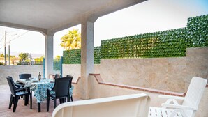 Un patio al aire libre con una mesa dispuesta para comer, rodeado de sillas.