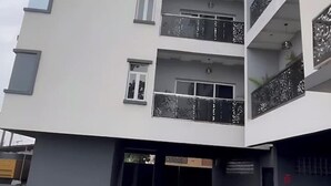 Un edificio de varios pisos con balcones, garaje y entrada protegida por una reja.