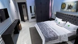 Un dormitorio moderno con una cama grande, un televisor montado en la pared y un armario.