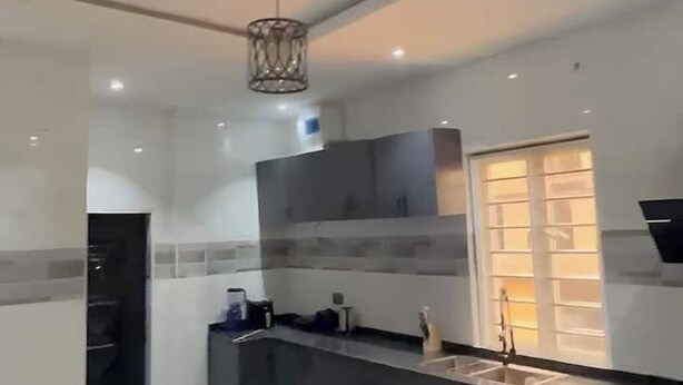 Una cocina moderna con salpicadero de mármol, horno empotrado y ventana con persianas.