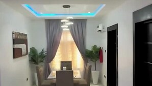 Un comedor moderno con una mesa, sillas, una lámpara en el techo y un ventanal con cortinas.
