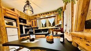 Una cucina rustica con mobili in legno, un piano di lavoro nero e un'area pranzo con sedie bianche.