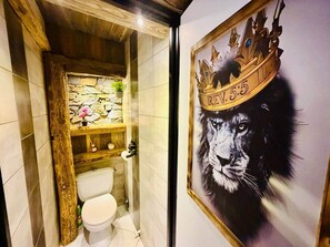 A bathroom with a stone wall, wooden shelf, and a framed artwork of a lion's face with a crown. - Elias - Luxury Apartment for 7 People - Aussois   (Aussois)