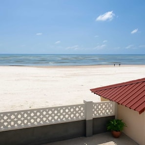 A beach view with a white fence, a potted plant, and a building with a red roof. - Serene Beachfront Bungalow Escape in Uroa, Zanzibar (Uroa)