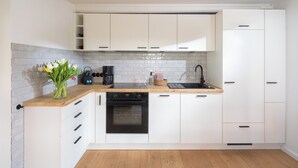 Eine moderne Küche mit weißen Schränken, einer Holz Arbeitsplatte, einem eingebauten Backofen und einer Kaffeemaschine.