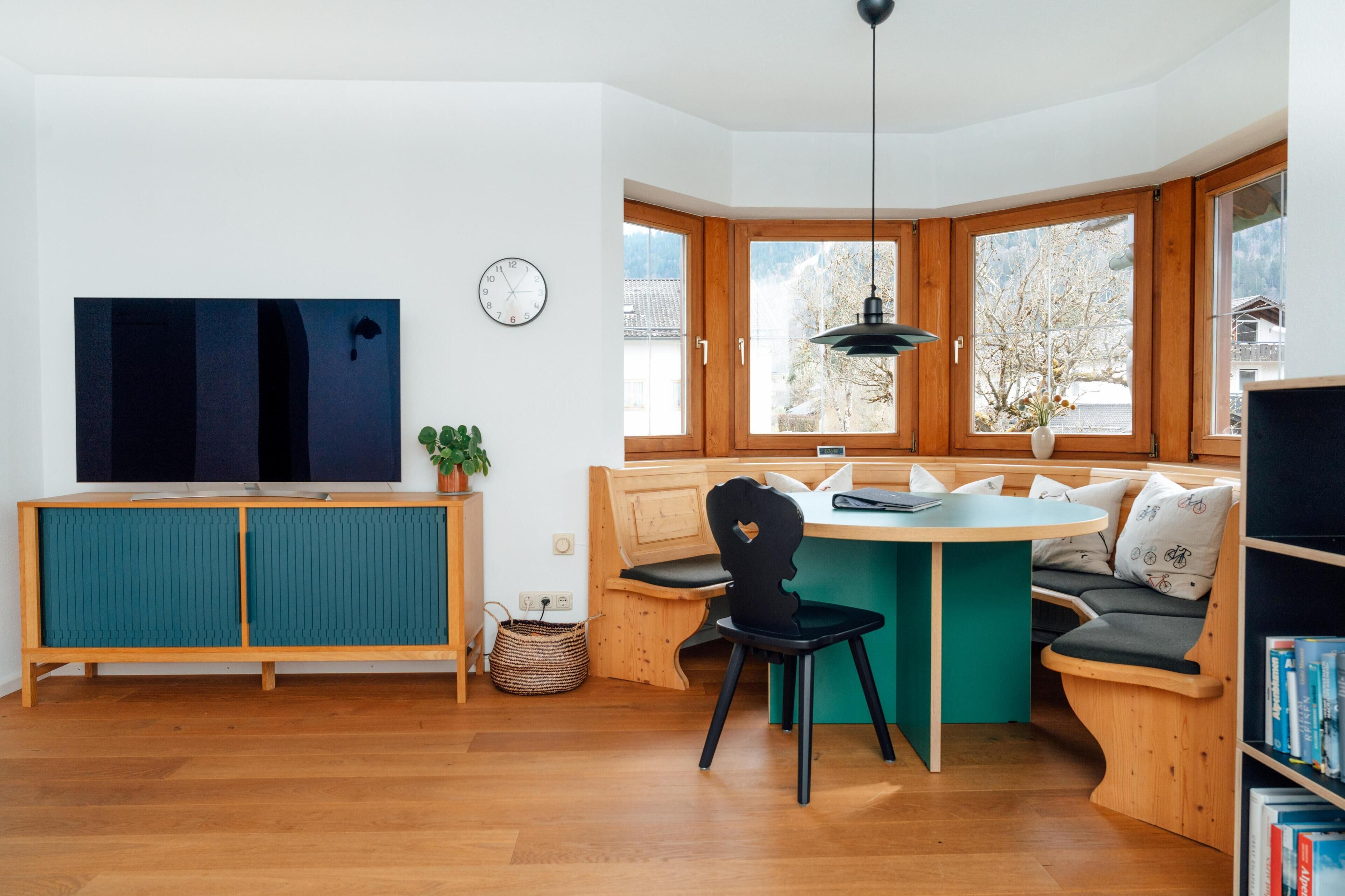 Eine moderne Küche mit einem Holzschrank, einem Esstisch und einer eingebauten Bank mit Kissen.