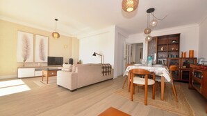 Una sala moderna con un sofá, televisor y mesa de comedor.