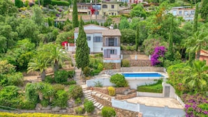 A hillside residential area with a pool, stone steps, and lush greenery.