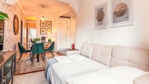 Een hotelkamer met een bed, een slaapbank, een eethoek met stoelen en een tafel, en een keuken.