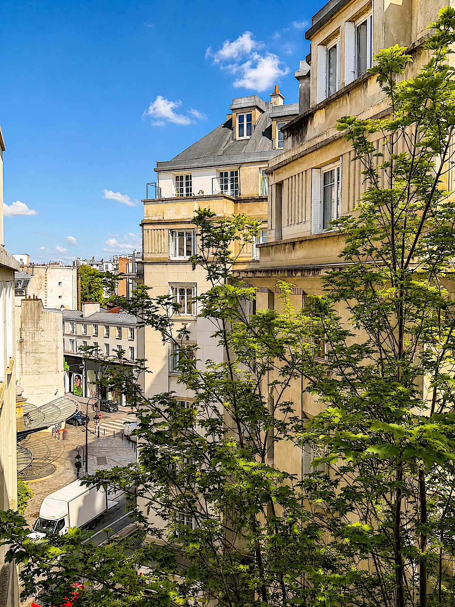 A multi-story building with balconies, a street below, and trees in the foreground.