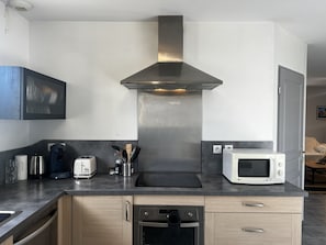 Une cuisine moderne dotée d’appareils électroménagers en acier inoxydable, de meubles en bois et d’un four à micro-ondes encastré.