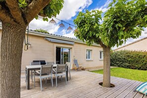 Un patio con mesa y sillas, una parrilla y un árbol.