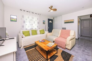 Una sala de estar con sofá, mesa de centro, televisor y ventilador de techo.
