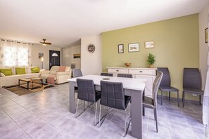 En moderne stue med spiseplads, en sofasæt, et sofabord og et spisebord med stole.