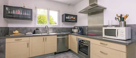 Una cocina moderna con campana de acero inoxidable, microondas y lavavajillas.