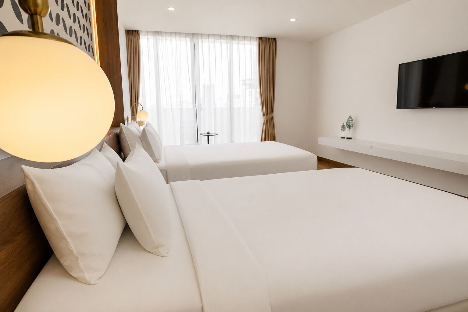 A hotel room with two beds, a TV on the wall, and a window with curtains.