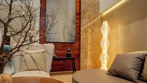 A modern living room with a sofa, a round table, and a decorative vase. - The Scenic Hotel  (Phnom Penh)
