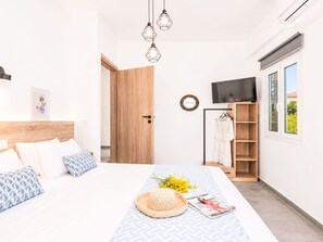 Una camera da letto moderna con un letto, un comodino, un armadio e una televisione.