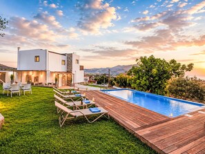 Una casa moderna con piscina, terraza de madera y césped.