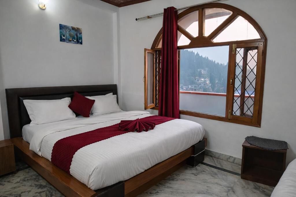 A bedroom with a bed, a window with a view of a mountain, and a painting on the wall.