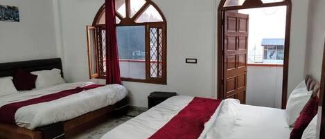 Een hotelkamer met twee bedden, een marmeren vloer, houten hoofdeinden en grote, rondbogenramen.