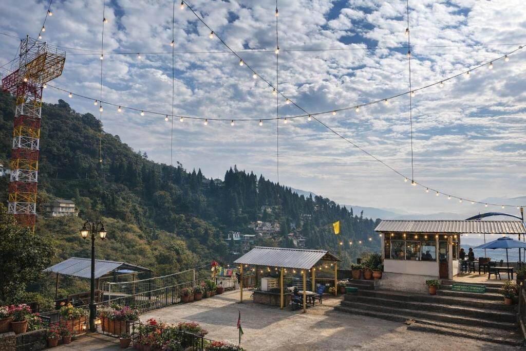 A terrace with string lights, a gazebo, and a view of a mountainous landscape.
