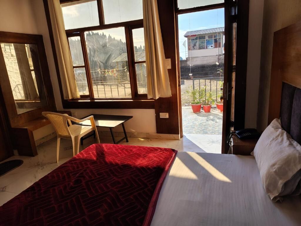 A hotel room with a bed, a desk, and a view of the outside.