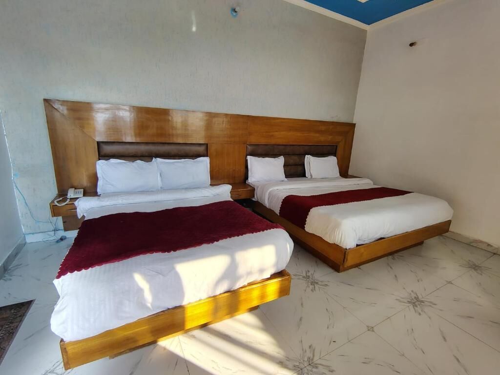 Een kamer met twee houten bedden, witte beddengoed en een rode plaid.