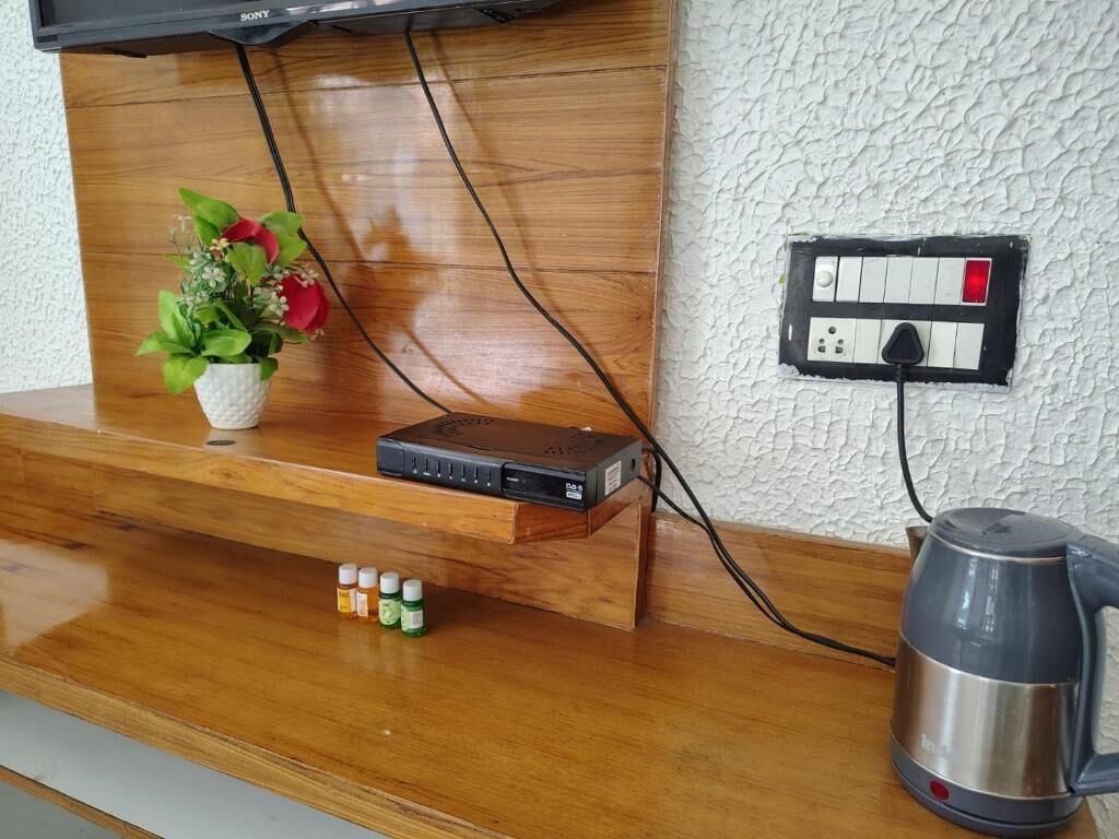 A wooden counter with a Sony TV mounted above it, a power outlet, and a kettle on the right.