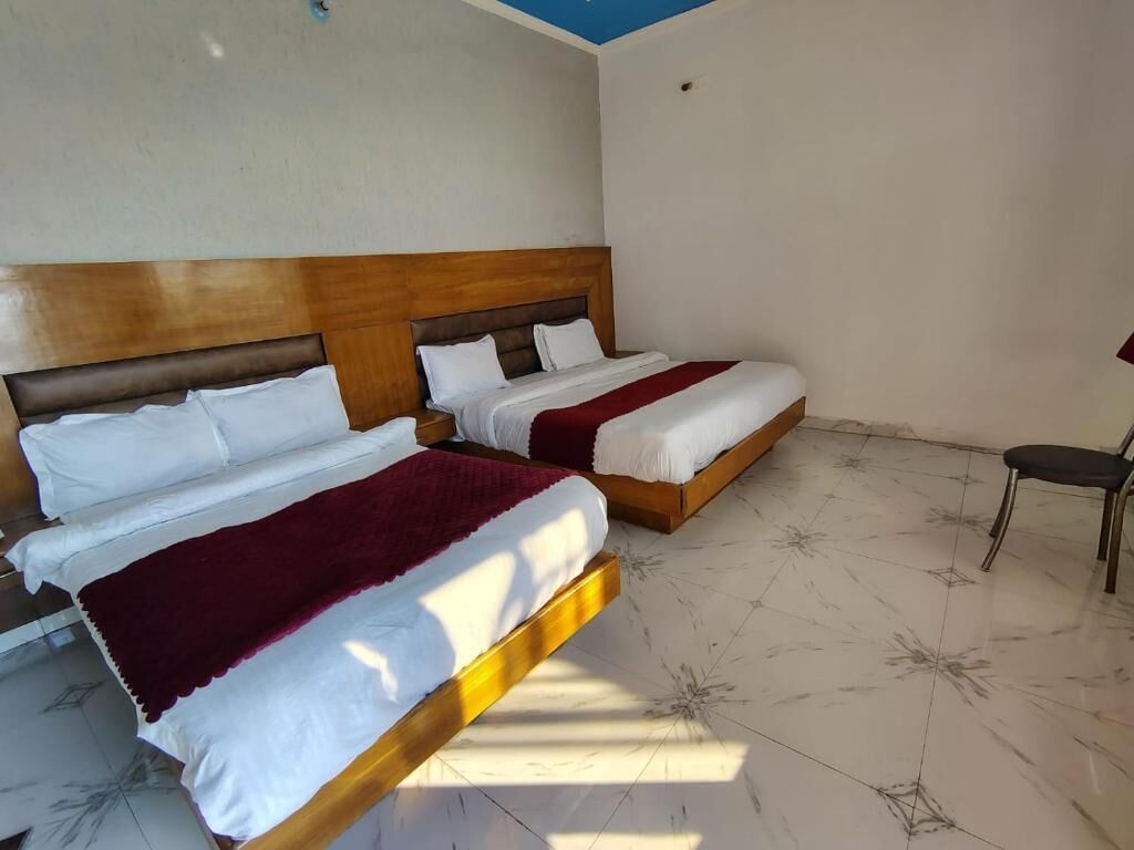 A hotel room with two beds, a wooden headboard, a chair, and a tiled floor.