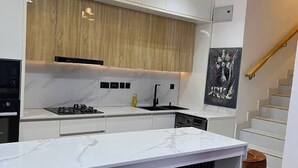 Una cocina moderna con encimera de mármol, armarios de madera y grifo negro.