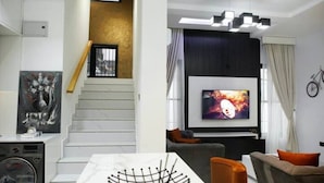 Una sala de estar moderna con una escalera, un televisor de pantalla plana y una zona de comedor.