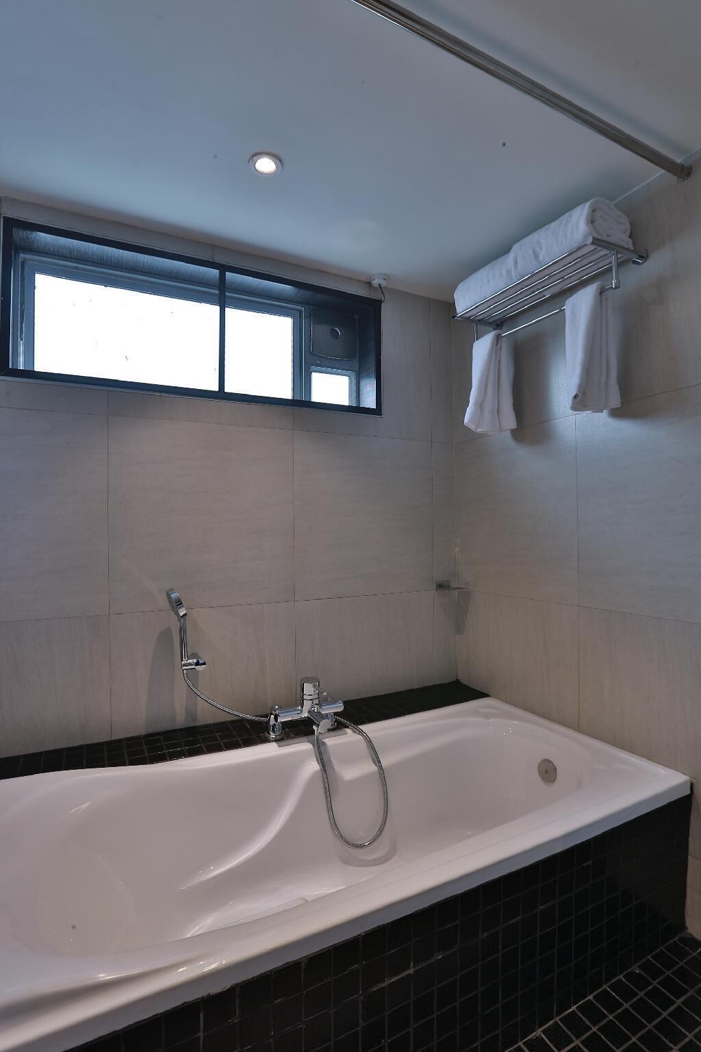 Une salle de bain avec une baignoire, une fenêtre et un porte-serviettes.