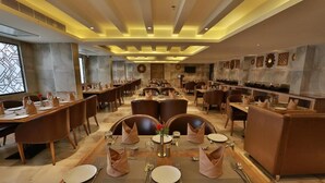 Un'ampia sala da pranzo con diversi tavoli e sedie, in un ambiente moderno ed elegante.