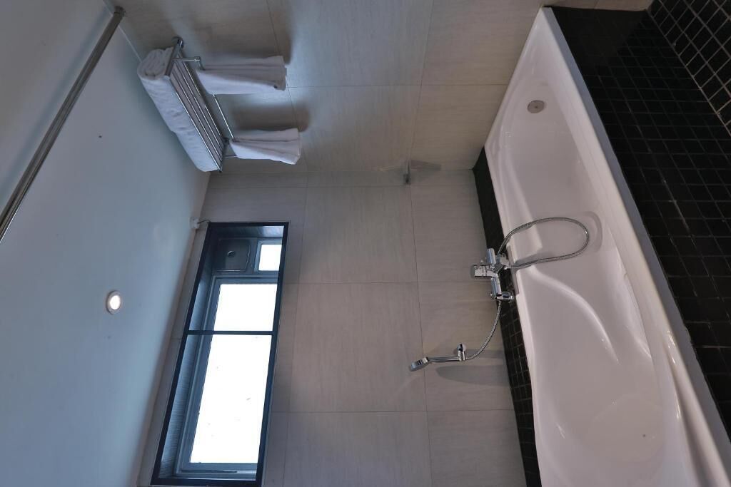A bathroom with a bathtub, a window, and a towel rack.