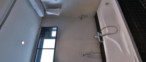 A bathroom with a bathtub, a window, and a towel rack.