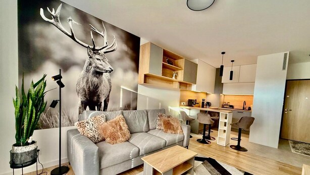 A modern living room with a grey sofa, a coffee table, and a large deer mural on the wall. - Jarzebinowa Loft by JumpInHere (Nowy Dwór Mazowiecki)