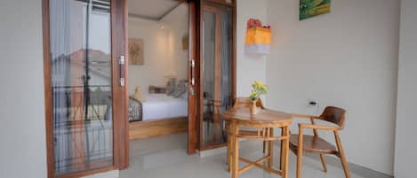 Une pièce comprenant une table et des chaises en bois, une porte-fenêtre coulissante et un lit donnant sur une vue agréable.