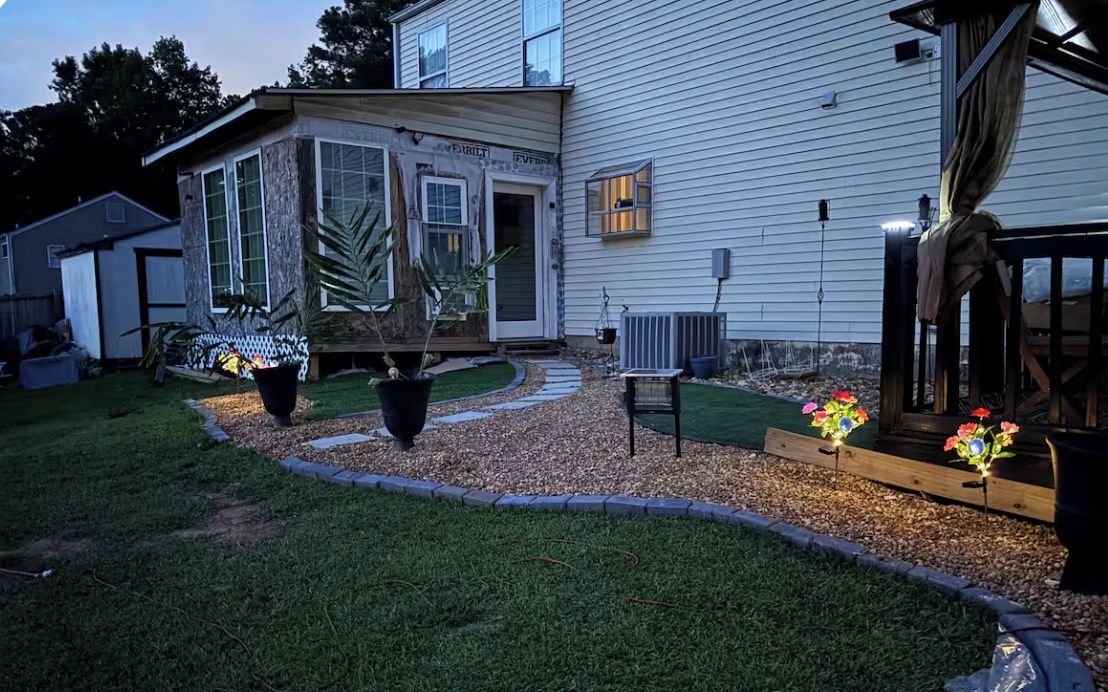A residential property with a well-maintained lawn, a pathway leading to the house, and outdoor lighting.
