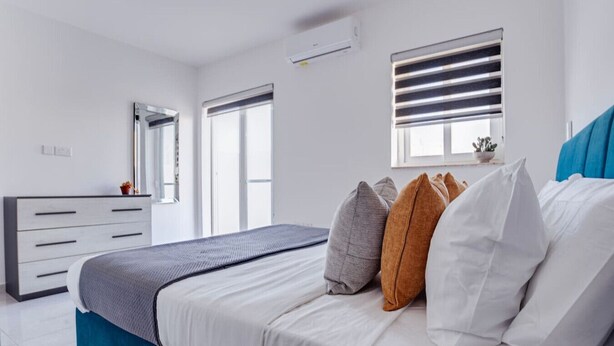 Ein Schlafzimmer mit Bett, Schminktisch, Fenster und Deckenventilator.