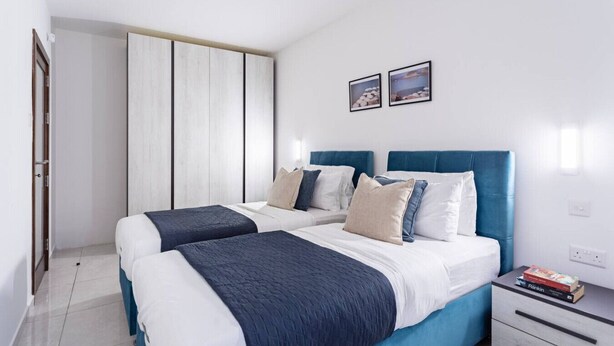 Een moderne slaapkamer met twee bedden, een garderobe en een nachtkastje met boeken.