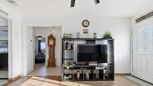 Ein Wohnzimmer mit Fernseher, Regalen mit Dekoration, einer Uhr und einer Tür mit einem Schild.