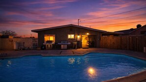 Ein Garten mit Swimmingpool, Grillplatz und einem Haus mit Holzzaun.