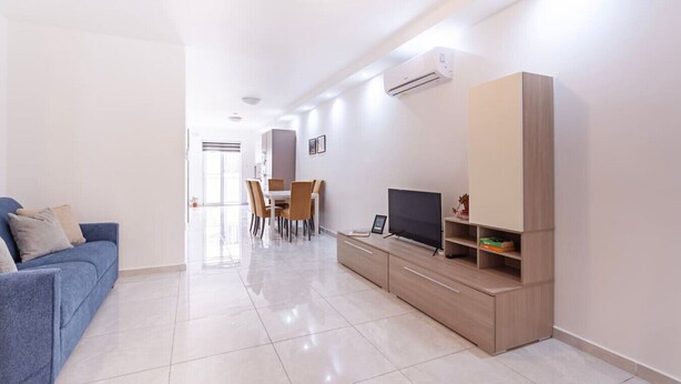 Una sala de estar moderna con sofá, televisor y mueble de entretenimiento.