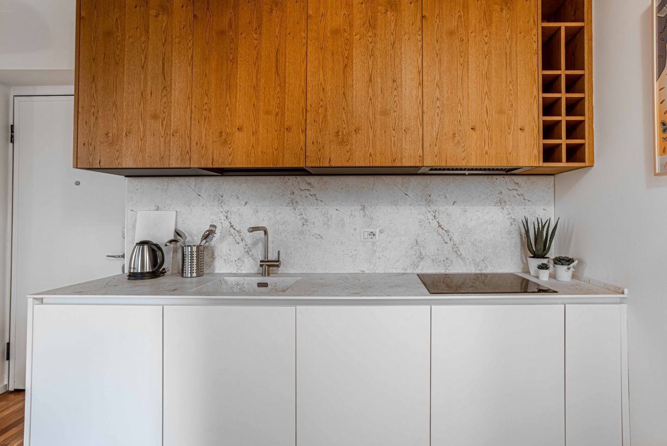 Une cuisine moderne avec des meubles en bois, un plan de travail en marbre et un meuble à vin intégré.