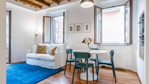 A modern living room with a white sofa, green chairs, a round table, and a blue rug. - Easylife - Milano - Mora 2 - Ticinese  (Milano)