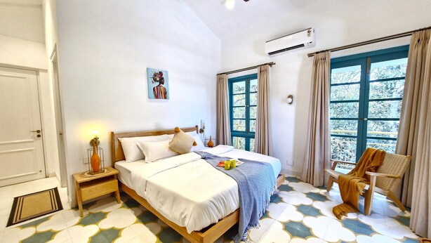 A bedroom with a bed, a chair, a window, and a ceiling fan. - Celest 3bhk Villa Siolim Pvt Pool Dancenter (Siolim)