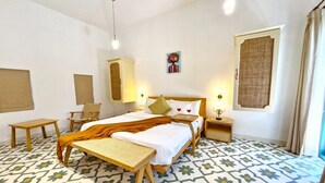 A hotel room with a bed, a bench, a chair, a bedside table, and a wall-mounted lamp. - Celest 3bhk Villa Siolim Pvt Pool Dancenter (Siolim)