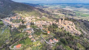 Vista aerea di una città storica con una piazza centrale, circondata da edifici a gradoni e da un'imponente torre.