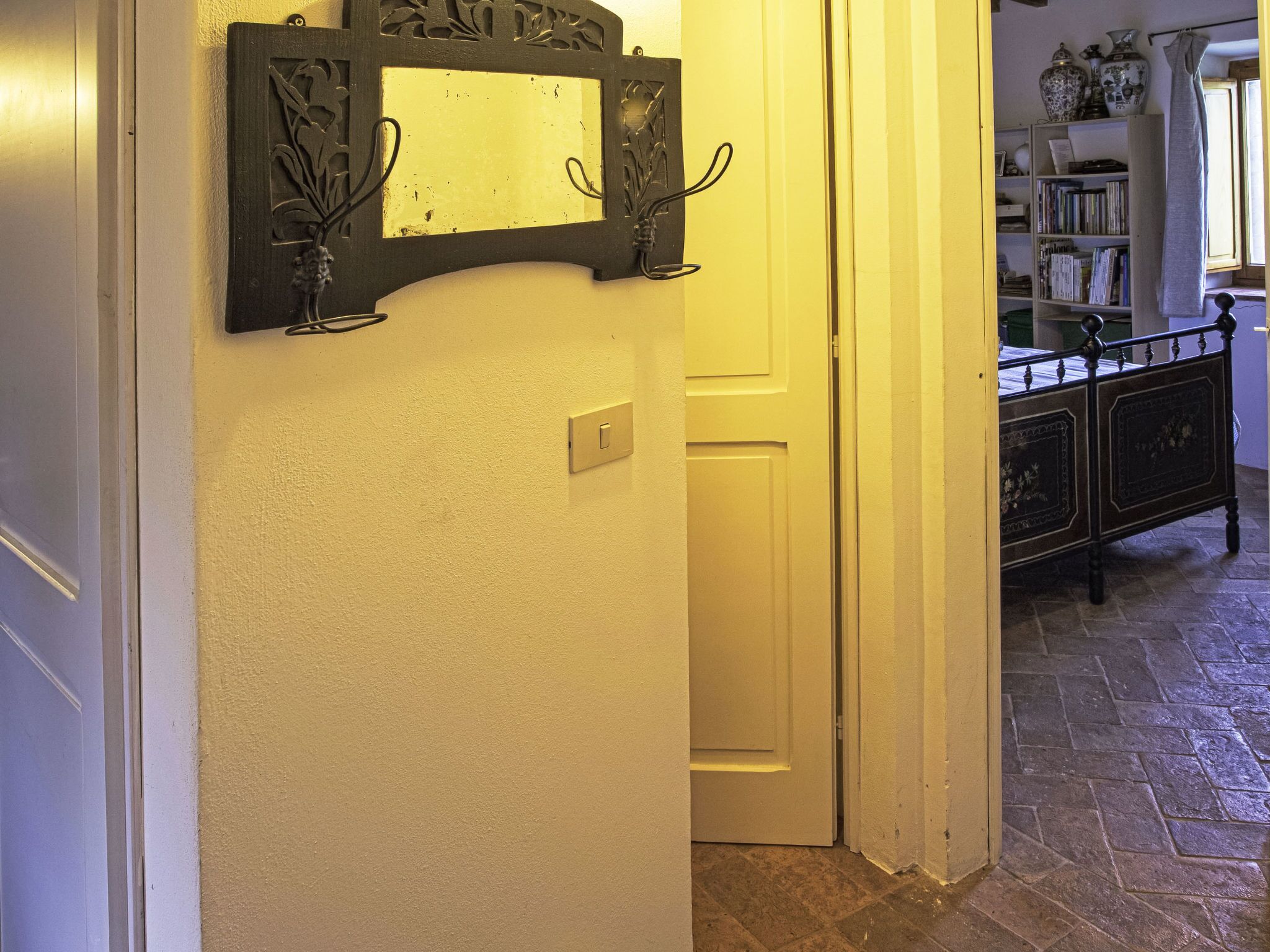 A hallway with a door, a light switch, and a metal decorative piece on the wall.
